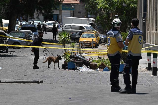 A security personnel along with a sniffer dog inspects near the Four Seasons Hotel following two blasts, in Damascus on July 7, 2026. Two explosions shook Damascus on July 7 near a hotel where French President Emmanuel Macron was staying, wounding at least 18 people, during the French leader's landmark visit to Syria. (Photo by LOUAI BESHARA / AFP)