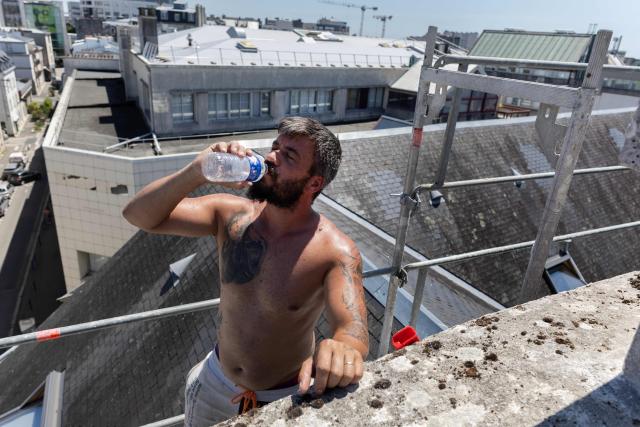 A worker drinks water in Brest, western France, on July 7, 2026 as another heatwave hits France. (Photo by Fred TANNEAU / AFP)