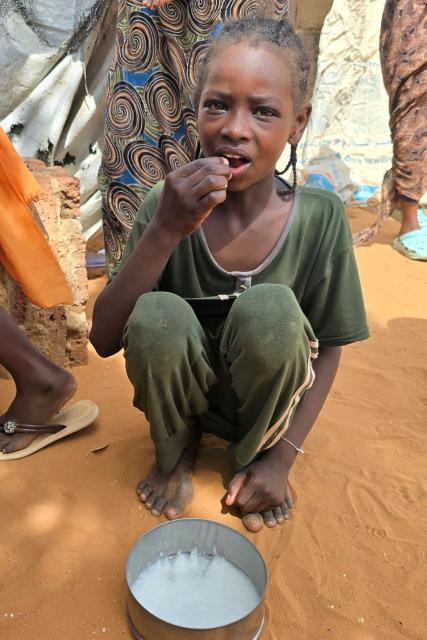 A Sudanese receives food distributed in al-Rahmaniyah camp for displaced people, near the city of El-Obeid in the southern Kordofan region on July 7, 2026. El-Obeid, a city of half a million people that hosts nearly 100,000 refugees displaced by violence elsewhere, has, in recent weeks, faced its most intense attacks yet from the paramilitary Rapid Support Forces (RSF). After breaking a prolonged siege in February last year, the army has struggled to stop the RSF from reimposing a blockade through repeated drone strikes targeting the city, its infrastructure and the main highway out. (Photo by AFP)