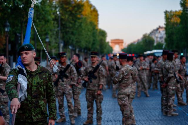 An Estonian army soldier looks on as he prepares to parade during a rehearsal of the annual Bastille Day military parade down the Champs Elysees Avenue, with the Arc de Triomphe in the background in Paris on July 8, 2026. (Photo by Dimitar DILKOFF / AFP)