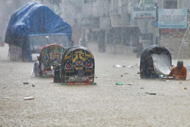Rickshaw pullers wade through a flooded street after heavy rains in Chittagong on July 8, 2026. (Photo by AFP)