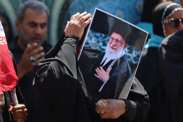 A woman holds a picture of the late Iranian supreme leader Ayatollah Ali Khamenei near the shrine of Imam Hussein in the Iraqi holy city of Karbala on July 8, 2026. Iran began six days of public funeral ceremonies for Khamenei on July 4, including a dedicated day in neighbouring Iraq -- a Shia powerhouse with close ties to Tehran and home to the faith's most sacred shrines. (Photo by AHMAD AL-RUBAYE / AFP)