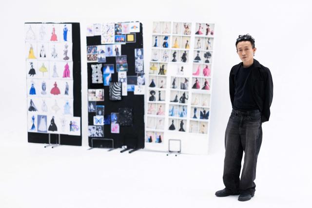 Hong-Kong born and London based Fashion designer Robert Wu poses for pictures next to a board displaying all the models of his collection, during a fitting session his atelier in Paris on July 7, 2026 on the eve of the Robert Wun Women Haute Couture Fall/Winter 2026-2027 collection as part of the Paris Fashion Week. Hong Kong-born designer Robert Wun has not had a holiday in years, but he's not complaining. In 2021, he was working from his kitchen -- now he dresses some of the world's best-known entertainers. In just five years, the 34-year-old has rocketed from unknown to one of the most sought-after names in the fashion world, designing for everyone from Lady Gaga, Beyonce to rapper Cardi B. (Photo by JOEL SAGET / AFP)