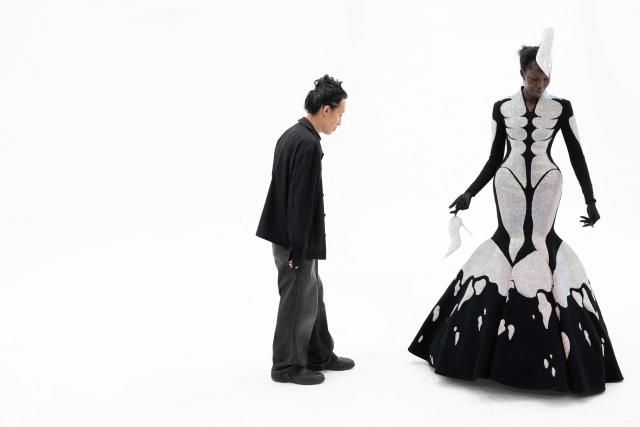 Hong-Kong born and London based Fashion designer Robert Wu looks a a model wearing one of his creations in his atelier in Paris on July 7, 2026 during a fitting session on the eve of the Robert Wun Women Haute Couture Fall/Winter 2026-2027 collection as part of the Paris Fashion Week. Hong Kong-born designer Robert Wun has not had a holiday in years, but he's not complaining. In 2021, he was working from his kitchen -- now he dresses some of the world's best-known entertainers. In just five years, the 34-year-old has rocketed from unknown to one of the most sought-after names in the fashion world, designing for everyone from Lady Gaga, Beyonce to rapper Cardi B. (Photo by JOEL SAGET / AFP)