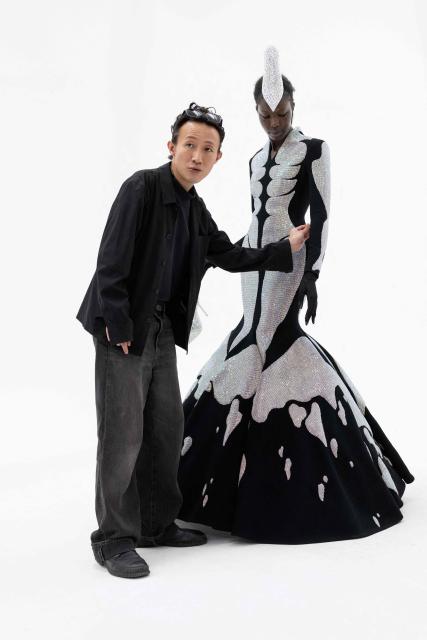 Hong-Kong born and London based Fashion designer Robert Wu looks a a model wearing one of his creations in his atelier in Paris on July 7, 2026 during a fitting session on the eve of the Robert Wun Women Haute Couture Fall/Winter 2026-2027 collection as part of the Paris Fashion Week. Hong Kong-born designer Robert Wun has not had a holiday in years, but he's not complaining. In 2021, he was working from his kitchen -- now he dresses some of the world's best-known entertainers. In just five years, the 34-year-old has rocketed from unknown to one of the most sought-after names in the fashion world, designing for everyone from Lady Gaga, Beyonce to rapper Cardi B. (Photo by JOEL SAGET / AFP)
