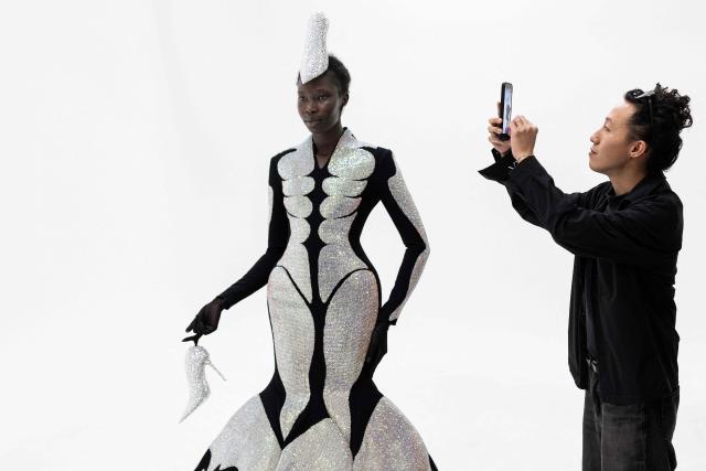 Hong-Kong born and London based Fashion designer Robert Wu looks a a model wearing one of his creations in his atelier in Paris on July 7, 2026 during a fitting session on the eve of the Robert Wun Women Haute Couture Fall/Winter 2026-2027 collection as part of the Paris Fashion Week. Hong Kong-born designer Robert Wun has not had a holiday in years, but he's not complaining. In 2021, he was working from his kitchen -- now he dresses some of the world's best-known entertainers. In just five years, the 34-year-old has rocketed from unknown to one of the most sought-after names in the fashion world, designing for everyone from Lady Gaga, Beyonce to rapper Cardi B. (Photo by JOEL SAGET / AFP)