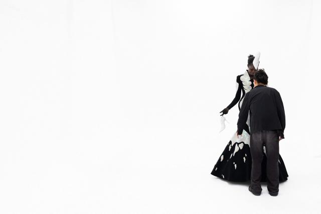 Hong-Kong born and London based Fashion designer Robert Wu looks at a model wearing one of his creations in his atelier in Paris on July 7, 2026 during a fitting session on the eve of the Robert Wun Women Haute Couture Fall/Winter 2026-2027 collection as part of the Paris Fashion Week. Hong Kong-born designer Robert Wun has not had a holiday in years, but he's not complaining. In 2021, he was working from his kitchen -- now he dresses some of the world's best-known entertainers. In just five years, the 34-year-old has rocketed from unknown to one of the most sought-after names in the fashion world, designing for everyone from Lady Gaga, Beyonce to rapper Cardi B. (Photo by JOEL SAGET / AFP)