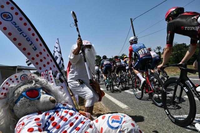 The pack of riders (peloton) cycles past a spectator in costume along the roadside during the 5th stage of the 113th edition of the Tour de France cycling race, 158,3 km between Lannemezan and Pau in southwestern France, on July 8, 2026. (Photo by Jeff PACHOUD / AFP)