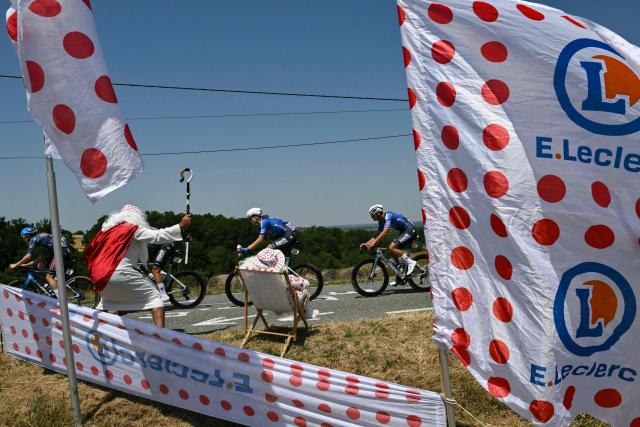 The pack of riders (peloton) cycles past a spectator in costume along the roadside during the 5th stage of the 113th edition of the Tour de France cycling race, 158,3 km between Lannemezan and Pau in southwestern France, on July 8, 2026. (Photo by Jeff PACHOUD / AFP)