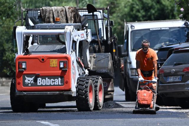 Workers repair a road under the sun at a construction site in Rome on July 8, 2026, as parts of Europe experience another heatwave. (Photo by Andreas SOLARO / AFP)