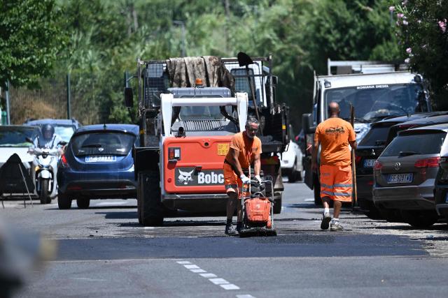 Workers repair a road under the sun at a construction site in Rome on July 8, 2026, as parts of Europe experience another heatwave. (Photo by Andreas SOLARO / AFP)