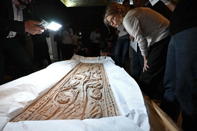 Officials look at an artifact from the city of Raqqa in northern Syria, dating back to the 9th century AD, during the process of the opening the crates of artifacts recovered from France at the National Museum in Damascus on July 8, 2026. The 23 objects returned to the National Museum of Damascus, span a period from prehistory through to the Abbasid era and include artefacts covering the Mesopotamian, Canaanite, Nabataean, Palmyrene, Roman, Byzantine and Umayyad civilisations, according to a statement from the Elysee Palace. (Photo by LOUAI BESHARA / AFP)