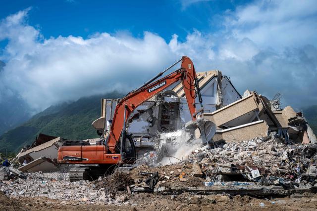 A backhoe is used on the ruins of a building destroyed by the June 24 earthquakes in Caraballeda, La Guaira state, Venezuela, on July 8, 2026. Venezuela's government called on July 8, 2026 for the release of frozen assets to help raise funds for the country's recovery from last month's twin earthquakes that killed at least 3,600 people. (Photo by Miguel MEDINA / AFP)
