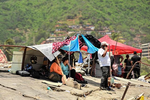 Families camp on top of the ruins of a building as they wait for the recovery of the corpses of their relatives, in Caraballeda, La Guaira state, Venezuela, on July 8, 2026, after the June 24 earthquakes. Venezuela's government called on July 8, 2026 for the release of frozen assets to help raise funds for the country's recovery from last month's twin earthquakes that killed at least 3,600 people. (Photo by MARTIN BERNETTI / AFP)