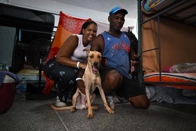 People pose with a dog inside a shelter at the Escuela Bolivariana 10 de Marzo in Maiquetia, La Guaira state, Venezuela, on July 8, 2026, following earthquakes that struck the region. Venezuela's government called on July 8, 2026 for the release of frozen assets to help raise funds for the country's recovery from last month's twin earthquakes that killed at least 3,600 people. (Photo by Raul ARBOLEDA / AFP)