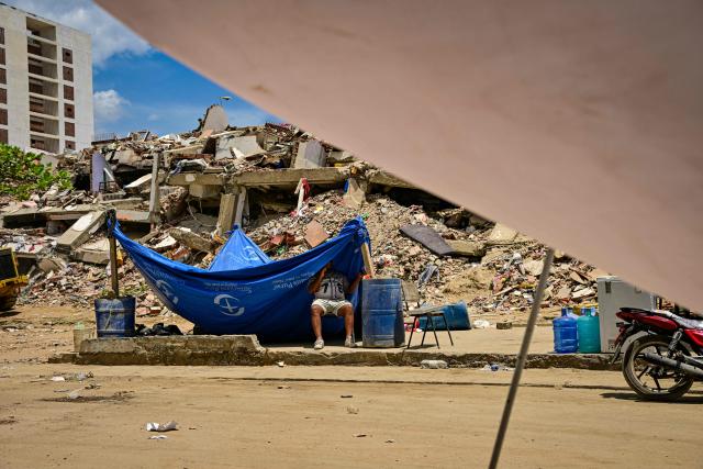 A man camps near the ruins of a building as he waits for the recovery of corpses of relatives, in Caraballeda, La Guaira state, Venezuela, on July 8, 2026, after the June 24 earthquakes. Venezuela's government called on July 8, 2026 for the release of frozen assets to help raise funds for the country's recovery from last month's twin earthquakes that killed at least 3,600 people. (Photo by MARTIN BERNETTI / AFP)