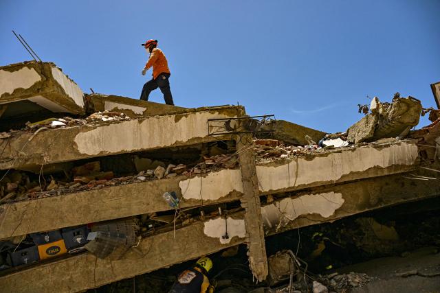 A Venezuelan rescue worker walk over the ruins of a building in Caraballeda, La Guaira state, Venezuela, on July 8, 2026, after the June 24 earthquakes. Venezuela's government called on July 8, 2026 for the release of frozen assets to help raise funds for the country's recovery from last month's twin earthquakes that killed at least 3,600 people. (Photo by MARTIN BERNETTI / AFP)
