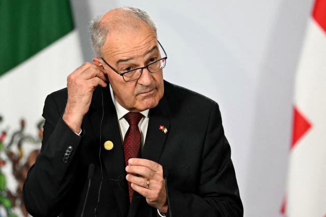 Switzerland’s President of the Confederation and Economy Minister Guy Parmelin adjusts an earpiece during a joint press conference with Mexico's President Claudia Sheinbaum (out of frame) at the National Palace in Mexico City on July 8, 2026. (Photo by Yuri CORTEZ / AFP)