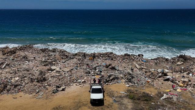 This aerial picture shows people dumping rubble near La Caleta beach in Taraguarena, in the state of La Guaira, Venezuela, on July 8, 2026. Venezuela's government called on July 8, 2026 for the release of frozen assets to help raise funds for the country's recovery from last month's twin earthquakes that killed at least 3,600 people. (Photo by Miguel MEDINA / AFP)