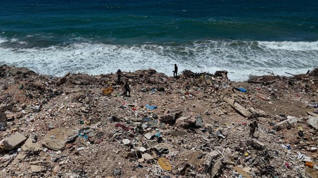 This aerial picture shows people searching for scrap metal in the rubble near La Caleta beach in Taraguarena, in the state of La Guaira, Venezuela, on July 8, 2026. Venezuela's government called on July 8, 2026 for the release of frozen assets to help raise funds for the country's recovery from last month's twin earthquakes that killed at least 3,600 people. (Photo by Miguel MEDINA / AFP)