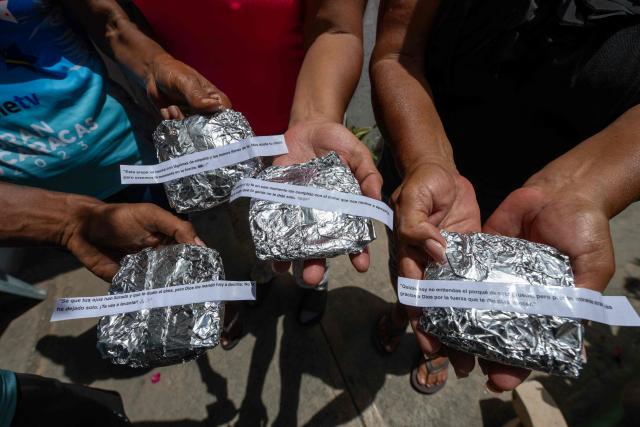 Residents hold arepas wrapped in aluminum foil, each with a small slip of paper bearing a message of hope in Taraguanena, in the state of La Guaira, Venezuela, on July 8, 2026. Venezuela's government called on July 8, 2026 for the release of frozen assets to help raise funds for the country's recovery from last month's twin earthquakes that killed at least 3,600 people. (Photo by Miguel MEDINA / AFP)