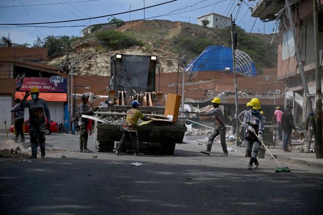 Workers clear debris from a street following powerful earthquakes in Catia La Mar, La Guaira state, Venezuela, on July 8, 2026. Venezuela's government called on July 8, 2026 for the release of frozen assets to help raise funds for the country's recovery from last month's twin earthquakes that killed at least 3,600 people. (Photo by Raul ARBOLEDA / AFP)