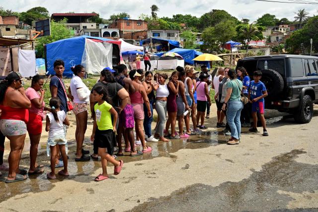 People queue to receive humanitarian aid in Playa Grande, Catia La Mar, La Guaira state, Venezuela, on July 8, 2026, following powerful earthquakes that struck the region. Venezuela's government called on July 8, 2026 for the release of frozen assets to help raise funds for the country's recovery from last month's twin earthquakes that killed at least 3,600 people. (Photo by MARTIN BERNETTI / AFP)