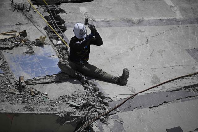 A rescue worker uses a hammer amid the rubble of collapsed buildings following the June 24 earthquakes in Catia La Mar, La Guaira state, Venezuela on July 8, 2026. Venezuela's government called on July 8, 2026 for the release of frozen assets to help raise funds for the country's recovery from last month's twin earthquakes that killed at least 3,600 people. (Photo by Federico PARRA / AFP)