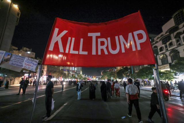Mourners walk past an anti-US banner as they arrive to attend the funeral of slain Iranian leader Ali Khamenei and members of his family near Imam Reza's shrine in Mashhad early on July 9, 2026. Iranians were preparing on July 9 to bury their slain leader Ali Khamenei in his hometown of Mashhad in northeast Iran, as new US strikes threatened to trigger a fresh escalation in the Middle East war. The late supreme leader's burial follows a multi-day funeral ceremony that attracted millions of mourners across various cities in both Iran and Iraq. (Photo by ATTA KENARE / AFP) / 