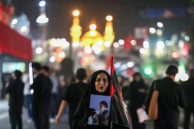 TOPSHOT - A woman along with others arrives to attend the funeral of slain Iranian leader Ali Khamenei and members of his family near Imam Reza's shrine in Mashhad early on July 9, 2026. Iranians were preparing on July 9 to bury their slain leader Ali Khamenei in his hometown of Mashhad in northeast Iran, as new US strikes threatened to trigger a fresh escalation in the Middle East war. The late supreme leader's burial follows a multi-day funeral ceremony that attracted millions of mourners across various cities in both Iran and Iraq. (Photo by ATTA KENARE / AFP) / 
