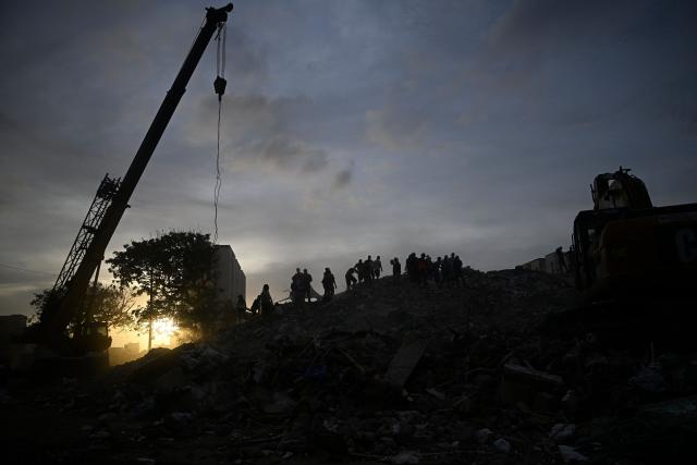 Rescuers and volunteers stand on the rubble of collapsed buildings following the June 24 earthquakes in Caraballeda, La Guaira state, Venezuela on July 8, 2026. Venezuela's government called on July 8, 2026 for the release of frozen assets to help raise funds for the country's recovery from last month's twin earthquakes that killed at least 3,600 people. (Photo by Federico PARRA / AFP)