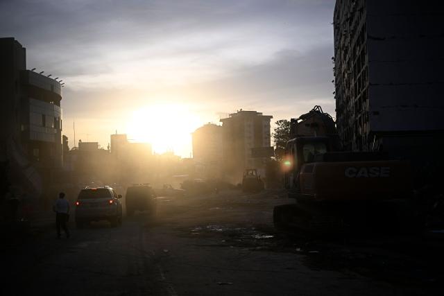 Vehicles drive along a dust-filled street lined with damaged buildings and heavy machinery following the June 24 earthquakes in Caraballeda, La Guaira state, Venezuela on July 8, 2026. Venezuela's government called on July 8, 2026 for the release of frozen assets to help raise funds for the country's recovery from last month's twin earthquakes that killed at least 3,600 people. (Photo by Federico PARRA / AFP)