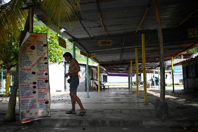 A man walks past closed food stalls in Naiguata, La Guaira state, Venezuela on July 8, 2026, following the June 24 earthquakes. Venezuela's government called on July 8, 2026 for the release of frozen assets to help raise funds for the country's recovery from last month's twin earthquakes that killed at least 3,600 people. (Photo by Federico PARRA / AFP)