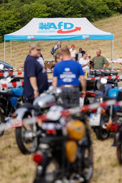 Participants attend an election campaign event of the far-right Alternative for Germany (AfD) party's and a motorbike and moped ride in Jessnitz, eastern Germany on June 28, 2026. Fans of far-right Alternative for Germany party's top candidate for the regional elections in Saxony-Anhalt, Ulrich Siegmund joined him for a countryside ride on Simson-brand scooters, that have become a symbol of East German identity. Descendants of the Simson firm's namesake Jewish founders, who gave up the company to escape persecution in Nazi Germany, have denounced the AfD's appropriation of the brand name. (Photo by Jens SCHLÜTER / AFP)