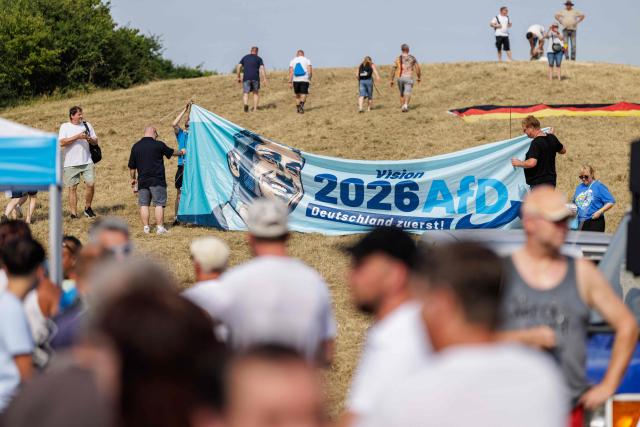 An advertising banner depicting Ulrich Siegmund, the far-right Alternative for Germany party's top candidate for the regional elections in Saxony-Anhalt is held an election campaign event of the far-right Alternative for Germany (AfD) party's and a motorbike and moped ride in Jessnitz, eastern Germany on June 28, 2026. Fans of far-right Alternative for Germany party's top candidate for the regional elections in Saxony-Anhalt, Ulrich Siegmund joined him for a countryside ride on Simson-brand scooters, that have become a symbol of East German identity. Descendants of the Simson firm's namesake Jewish founders, who gave up the company to escape persecution in Nazi Germany, have denounced the AfD's appropriation of the brand name. (Photo by Jens SCHLÜTER / AFP)