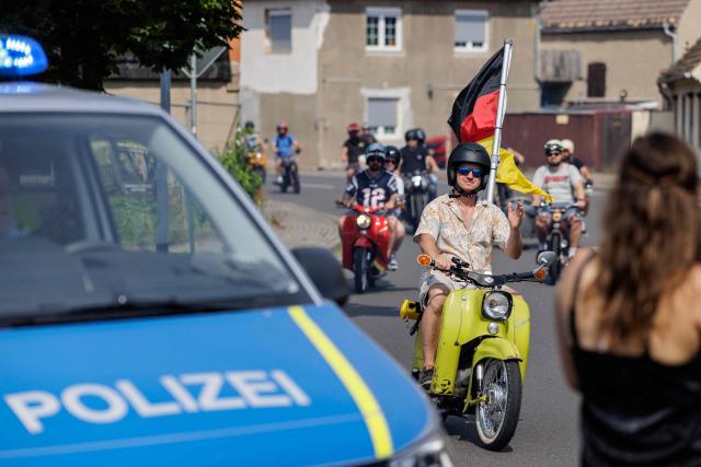 Participants ride Simson mopeds during an election campaign event of the far-right Alternative for Germany (AfD) party's and a motorbike and moped ride in Jessnitz, eastern Germany on June 28, 2026. Fans of far-right Alternative for Germany party's top candidate for the regional elections in Saxony-Anhalt, Ulrich Siegmund joined him for a countryside ride on Simson-brand scooters, that have become a symbol of East German identity. Descendants of the Simson firm's namesake Jewish founders, who gave up the company to escape persecution in Nazi Germany, have denounced the AfD's appropriation of the brand name. (Photo by Jens SCHLÜTER / AFP)