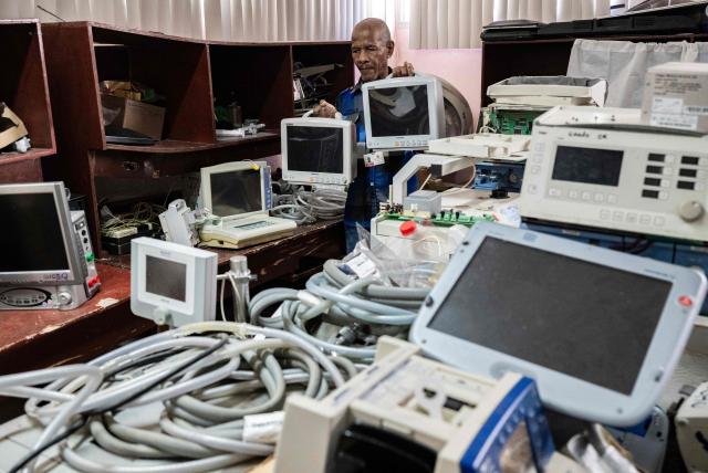Luis Alexis Duncan, a specialist in electromedicine, carries monitors to be repaired at the Electromedicine Workshop of the Institute of Cardiology and Cardiovascular Surgery in Havana on July 1, 2026. In the midst of one of the worst economic crises Cuba has experienced in decades, the health system is striving to maintain its services and priority programmes despite medicine and supply shortages, technological deterioration, staff shortages, prolonged power cuts and the impact of the United States sanctions. (Photo by YAMIL LAGE / AFP)