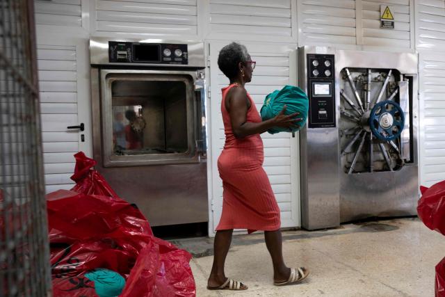 A woman carries medical-surgical material for sterilisation in an autoclave at the Hermanos Ameijeiras Clinical-Surgical Hospital in Havana on July 2, 2026. In the midst of one of the worst economic crises Cuba has experienced in decades, the health system is striving to maintain its services and priority programmes despite medicine and supply shortages, technological deterioration, staff shortages, prolonged power cuts and the impact of the United States sanctions. (Photo by YAMIL LAGE / AFP)