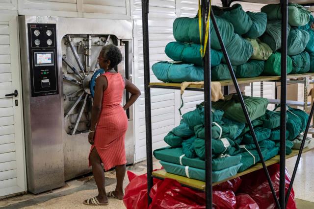 A woman waits in front of an autoclave for the sterilisation of medical-surgical material at the Hermanos Ameijeiras Clinical-Surgical Hospital in Havana on July 2, 2026. In the midst of one of the worst economic crises Cuba has experienced in decades, the health system is striving to maintain its services and priority programmes despite medicine and supply shortages, technological deterioration, staff shortages, prolonged power cuts and the impact of the United States sanctions. (Photo by YAMIL LAGE / AFP)