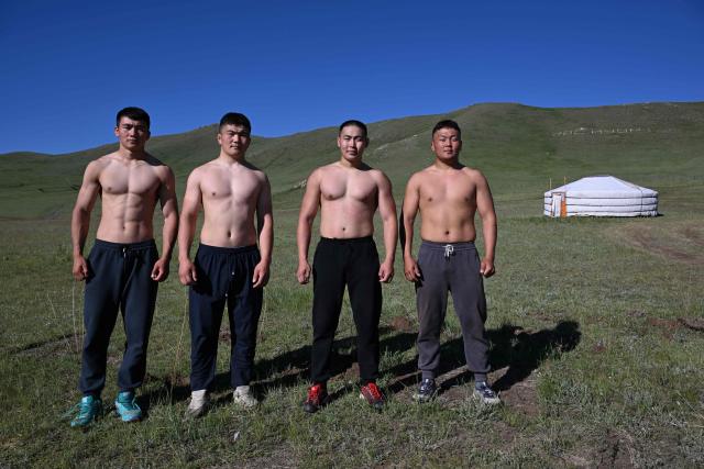 This photo taken on June 24, 2026 shows Mongolian wrestlers posing next to a traditional ger tent at a training camp ahead of the Naadam Festival on the outskirts of Ulaanbaatar. The whistle blows, sending dozens of hulking wrestlers chasing a football in the Mongolian grasslands -- a World Cup twist in their gruelling training for one of the country's oldest sporting traditions. (Photo by Adek BERRY / AFP) / To go with 'MONGOLIA-LIFESTYLE-TRADITION-WRESTLING,FOCUS' by Mungunsor Purevsuren