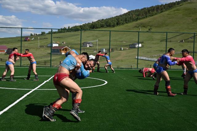 This photo taken on June 24, 2026 shows Mongolian wrestlers sparring at a training camp ahead of the Naadam Festival on the outskirts of Ulaanbaatar. The whistle blows, sending dozens of hulking wrestlers chasing a football in the Mongolian grasslands -- a World Cup twist in their gruelling training for one of the country's oldest sporting traditions. (Photo by Adek BERRY / AFP) / To go with 'MONGOLIA-LIFESTYLE-TRADITION-WRESTLING,FOCUS' by Mungunsor Purevsuren
