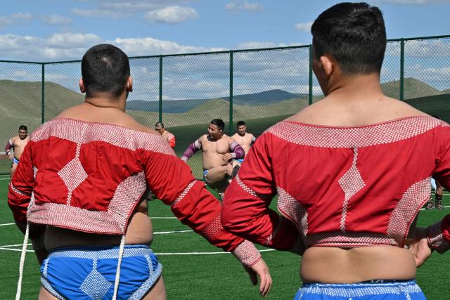 This photo taken on June 24, 2026 shows Mongolian wrestlers at a training camp ahead of the Naadam Festival on the outskirts of Ulaanbaatar. The whistle blows, sending dozens of hulking wrestlers chasing a football in the Mongolian grasslands -- a World Cup twist in their gruelling training for one of the country's oldest sporting traditions. (Photo by Adek BERRY / AFP) / To go with 'MONGOLIA-LIFESTYLE-TRADITION-WRESTLING,FOCUS' by Mungunsor Purevsuren