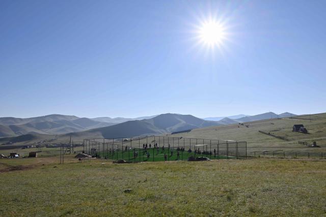 This photo taken on June 24, 2026 shows a general view of Mongolian wrestlers on a field at a training camp ahead of the Naadam Festival on the outskirts of Ulaanbaatar. The whistle blows, sending dozens of hulking wrestlers chasing a football in the Mongolian grasslands -- a World Cup twist in their gruelling training for one of the country's oldest sporting traditions. (Photo by Adek BERRY / AFP) / To go with 'MONGOLIA-LIFESTYLE-TRADITION-WRESTLING,FOCUS' by Mungunsor Purevsuren