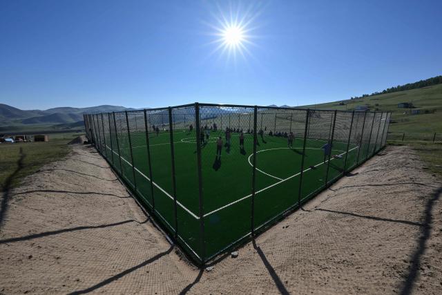 This photo taken on June 24, 2026 shows a general view of Mongolian wrestlers on a field at a training camp ahead of the Naadam Festival on the outskirts of Ulaanbaatar. The whistle blows, sending dozens of hulking wrestlers chasing a football in the Mongolian grasslands -- a World Cup twist in their gruelling training for one of the country's oldest sporting traditions. (Photo by Adek BERRY / AFP) / To go with 'MONGOLIA-LIFESTYLE-TRADITION-WRESTLING,FOCUS' by Mungunsor Purevsuren