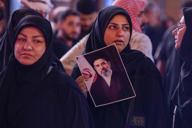 A woman holds a picture of the late Iranian supreme leader Ayatollah Ali Khamenei near the shrine of Imam Hussein in the Iraqi holy city of Karbala on July 9, 2026. Iranians were preparing on July 9 to bury their slain leader Ali Khamenei in his hometown of Mashhad in northeast Iran, as new US strikes threatened to trigger a fresh escalation in the Middle East war. The late leader's burial follows a multi-day funeral ceremony that attracted millions of mourners across various cities in both Iran and Iraq. (Photo by murtadha ridha / AFP)