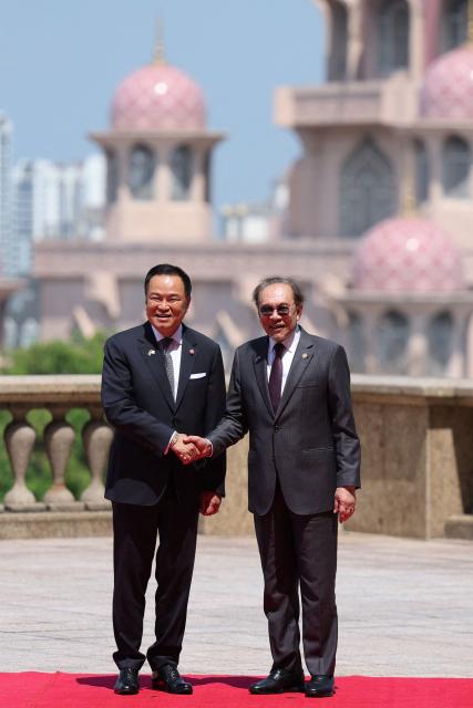 Thailand’s Prime Minister Anutin Charnvirakul shakes hands with Malaysia's Prime Minister Anwar Ibrahim with Putra Mosque in the background during Anuthin’s official visit, at the Federal Government office of Perdana Putra in Putrajaya on July 9, 2026. (Photo by Hasnoor Hussain / POOL / AFP)