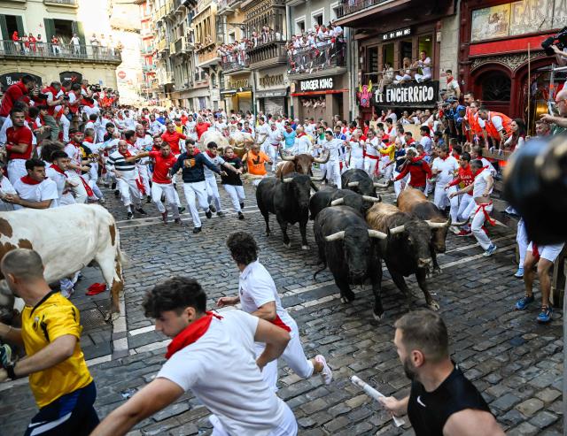 Participants run ahead of bulls from the Victoriano del Rio bull ranch during the third running of the bulls of the San Fermin festival in Pamplona, northern Spain, on July 9, 2026. Thousands of people every year attend the week-long festival and its famous 'encierros', or running of the bulls, in which six bulls are released at 8:00 a.m. evey day to run from their corral to the bullring through the narrow streets of the old town over an 850 meters (yards) course while runners ahead of them try to stay close to the bulls without falling over or being gored. (Photo by ANDER GILLENEA / AFP)