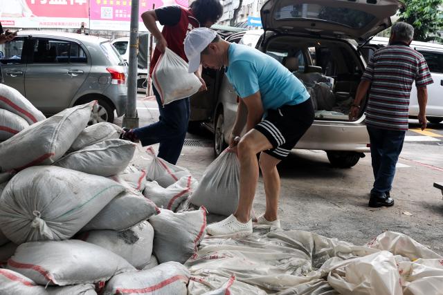 People load sandbags onto a truck as preparations are made ahead of the arrival of Typhoon Bavi, in Taipei on July 9, 2026 (Photo by I-Hwa Cheng / AFP)