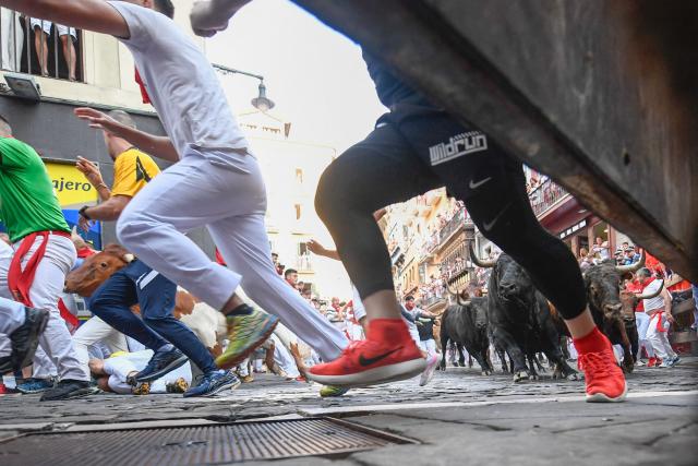 Participants run ahead of bulls from the Victoriano del Rio bull ranch during the third running of the bulls of the San Fermin festival in Pamplona, northern Spain, on July 9, 2026. Thousands of people every year attend the week-long festival and its famous 'encierros', or running of the bulls, in which six bulls are released at 8:00 a.m. evey day to run from their corral to the bullring through the narrow streets of the old town over an 850 meters (yards) course while runners ahead of them try to stay close to the bulls without falling over or being gored. (Photo by ANDER GILLENEA / AFP)