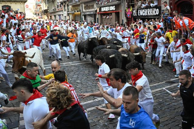 Bulls from the Victoriano del Rio bull ranch head into the Mercaderes curve as runners participate in the third running of the bulls of the San Fermin festival in Pamplona, northern Spain, on July 9, 2026. Thousands of people every year attend the week-long festival and its famous 'encierros', or running of the bulls, in which six bulls are released at 8:00 a.m. evey day to run from their corral to the bullring through the narrow streets of the old town over an 850 meters (yards) course while runners ahead of them try to stay close to the bulls without falling over or being gored. (Photo by ANDER GILLENEA / AFP)